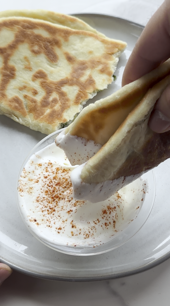 bolani being dipped into a yogurt cayenne pepper dip